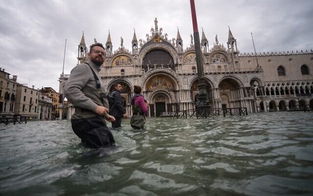 A general view shows people walking across the flooded St. Mark's Square, by St. Mark's Basilica on November 15, 2019 in Venice, two days after the city suffered its highest tide in 50 years (Filippo MONTEFORTE / AFP)