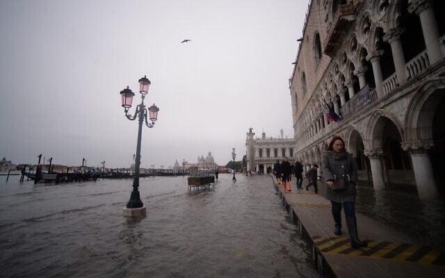 Visitors walk in flooded Venice, in the morning of November 17, 2019. (Photo by Filippo MONTEFORTE / AFP)