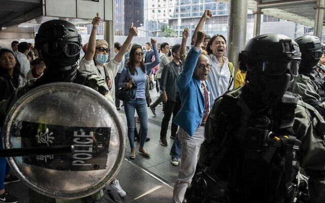 Riot police stand in between pro-China supporters (C) as they shout slogans and gesture towards office workers (not pictured) gathering in support of pro-democracy protesters during a lunch break rally in the Central district of Hong Kong on November 22, 2019. (NICOLAS ASFOURI / AFP) Riot police stand in between pro-China supporters (C) as they shout slogans and gesture towards office workers (not pictured) gathering in support of pro-democracy protesters during a lunch break rally in the Central district of Hong Kong on November 22, 2019. (NICOLAS ASFOURI / AFP)