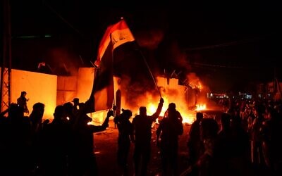Iraqi demonstrators gather as flames start consuming Iran's consulate in the southern Iraqi Shiite holy city of Najaf on November 27, 2019, two months into the country's most serious social crisis in decades. (AFP)