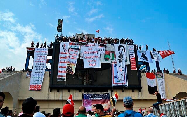 In this photo from October 30, 2019, Iraqi anti-government protesters hang their demands and slogans while standing on a building near Tahrir Square, Baghdad, Iraq. (AP Photo/Hadi Mizban) In this photo from October 30, 2019, Iraqi anti-government protesters hang their demands and slogans while standing on a building near Tahrir Square, Baghdad, Iraq. (AP Photo/Hadi Mizban)