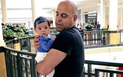 In this June 2016 photo provided by Guila Fakhoury, her father Amer Fakhoury holds his granddaughter, Kira, in King of Prussia, Pennsylvania. (Guila Fakhoury via AP)