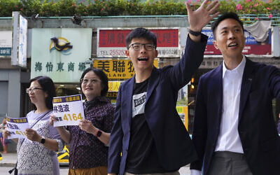 Election winner candidate Kelvin Lam, right, and pro-democracy activist Joshua Wong, second right, wave to people and thank for their support, outside South Horizons Station in Hong Kong, Monday, Nov. 25, 2019. (AP Photo/Vincent Yu)