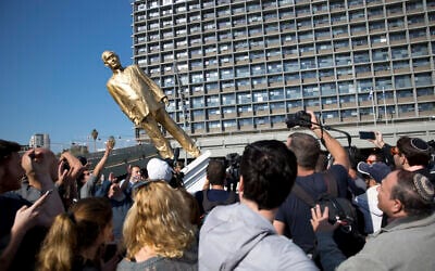 People watch a statue of Prime Minister Benjamin Netanyahu as it falls at Rabin square in Tel Aviv, Israel, Tuesday, Dec. 6, 2016. (AP Photo/Oded Balilty)
