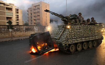 An army armored personnel carrier removes a garbage container set on fire by anti-government protesters in Beirut, Lebanon, Monday, Oct. 28, 2019. (AP/Hussein Malla)