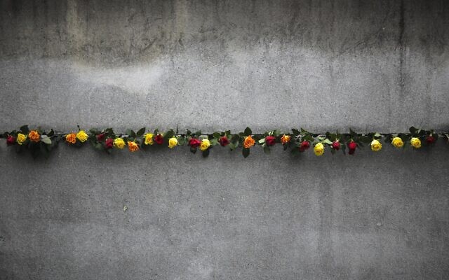 Flowers stuck in remains of the Berlin Wall during a commemoration ceremony to celebrate the 30th anniversary of the fall of the Berlin Wall at the Wall memorial side at Bernauer Strasse in Berlin, Nov. 9, 2019. (AP Photo/Markus Schreiber)