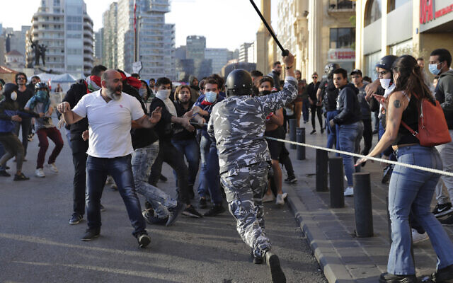 A police officer raises his baton to anti-government protesters during clashes in downtown Beirut, Lebanon, Nov. 19, 2019. (Hassan Ammar/AP) A police officer raises his baton to anti-government protesters during clashes in downtown Beirut, Lebanon, Nov. 19, 2019. (Hassan Ammar/AP)