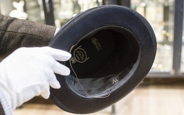 A man holds a hat with the initials of Adolf Hitler prior to an auction in Grasbrunn, Germany on Wednesday, November 20, 2019.  (Matthias Balk/dpa via AP)