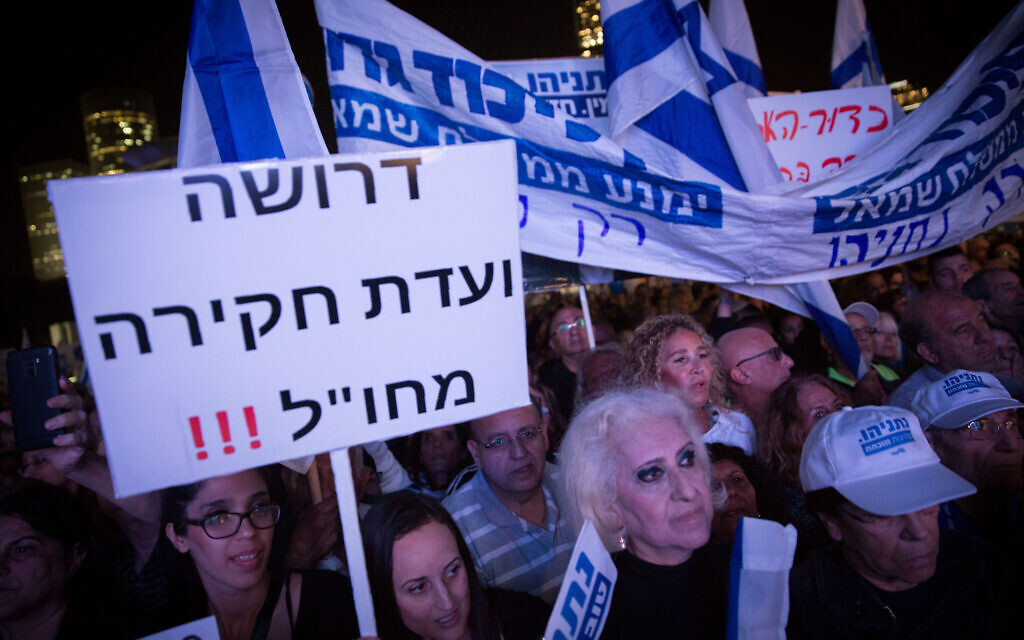 A supporter of Prime Minister Benjamin Netanyahu holds up sign saying 'We demand an overseas commission of inquiry' during a rally in Tel Aviv on November 26, 2019. Miriam Alster/Flash90)