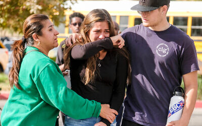 A student is comforted at a park following a shooting at Saugus High School that killed two, November 14, 2019, in Santa Clarita, California. (AP Photo/Ringo H.W. Chiu)