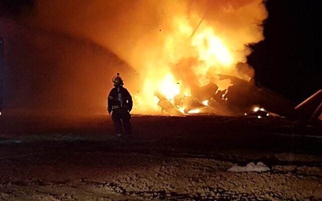 A firefighter works to extinguish the blaze engulfing a helicopter that made an emergency landing in a field outside of Rahat in the Negev desert on November 26, 2019. (Fire and Rescue Services) A firefighter works to extinguish the blaze engulfing a helicopter that made an emergency landing in a field outside of Rahat in the Negev desert on November 26, 2019. (Fire and Rescue Services)
