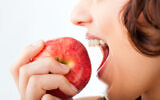 An illustrative image of a woman biting into an apple (kzenon; iStock by Getty Images)