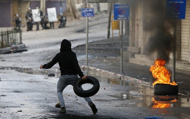 A Palestinian protester throws a tire during clashes with Israeli security forces in the southern West Bank city of Hebron, on December 9, 2019, amid a general strike over Israeli settlement activity. (HAZEM BADER / AFP) A Palestinian protester throws a tire during clashes with Israeli security forces in the southern West Bank city of Hebron, on December 9, 2019, amid a general strike over Israeli settlement activity. (HAZEM BADER / AFP)