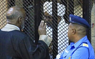Sudan's deposed president Omar al-Bashir sits in a defendant's cage during his corruption trial at a court in Khartoum on December 14, 2019. (AFP)