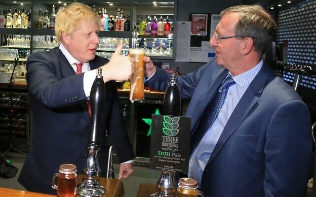 Britain's Prime Minister Boris Johnson gestures after pulling a pint with newly elected Conservative party MP for Sedgefield, Paul Howell, at Sedgefield Cricket Club in County Durham, north east England on December 14, 2019, following his Conservative party's general election victory. (Photo by Lindsey Parnaby / POOL / AFP) Britain's Prime Minister Boris Johnson gestures after pulling a pint with newly elected Conservative party MP for Sedgefield, Paul Howell, at Sedgefield Cricket Club in County Durham, north east England on December 14, 2019, following his Conservative party's general election victory. (Photo by Lindsey Parnaby / POOL / AFP)