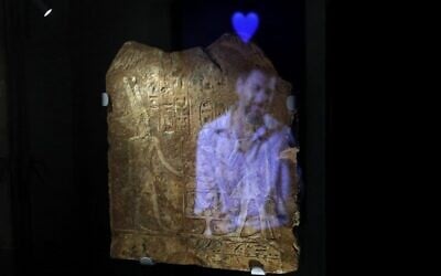 A video installation shows the image of a man with the emoji of a blue hart reflected on an ancient Egyptian plaque engraved with Hieroglyphs, at the exhibition "Emoglyphs: Picture-Writing from Hieroglyphs to the Emoji" at the Israel Museum in Jerusalem, on December 19, 2019. (MENAHEM KAHANA / AFP)