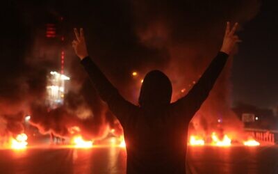 An Iraqi demonstrator gestures as tyres burn during a protest in Iraq's shrine city of Karbala, south of the capital Baghdad, on December 22, 2019. (Mohammed SAWAF / AFP)