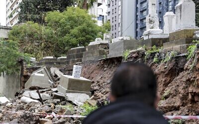 People look at graves damaged during bad weather in a winter storm at the Jewish cemetery in the Lebanese capital Beirut on December 26, 2019. (Anwar Amro/AFP)