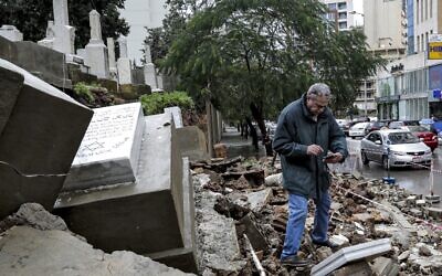 A man inspects graves damaged during bad weather in a winter storm at the Jewish cemetery in the Lebanese capital Beirut on December 26, 2019. (Anwar Amro/AFP)