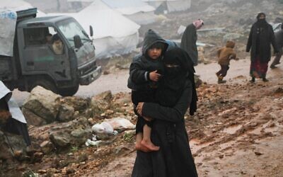 A Syrian woman who fled from government forces' advance on Maaret al-Numan in the south of the Idlib prvoince, carries a child at a camp for displaced people near the village of Harbnoush on December 27, 2019. (Aref TAMMAWI/AFP)