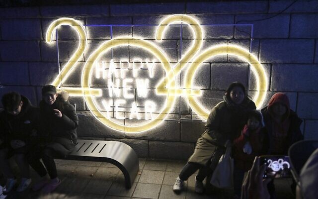 People pose for a picture in front of a 2020 luminous sign after midnight during a countdown event to mark the New Year in central Seoul on January 1, 2020. (Jung Yeon-je/AFP)