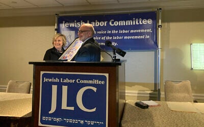 Jewish Labor Committee President Stuart Appelbaum, left, presenting Hillary Clinton with a poster portraying the Jewish immigrant experience in the US at the Sheraton New York Times Square Hotel, December 9, 2019. (Josefin Dolsten via JTA)