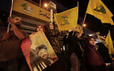 In this Oct. 25, 2019 file photo, supporters of Hezbollah leader Hassan Nasrallah hold his pictures and waves Hezbollah flags in the southern suburb of Beirut, Lebanon.  (AP Photo/Hassan Ammar)