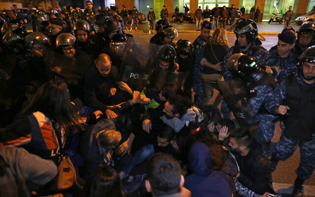 Anti-government protesters lie on a road, as they scream and hold each other while riot police try to remove them and open the road, in Beirut, Lebanon, December 4, 2019. (Bilal Hussein/AP) Anti-government protesters lie on a road, as they scream and hold each other while riot police try to remove them and open the road, in Beirut, Lebanon, December 4, 2019. (Bilal Hussein/AP)