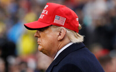 US President Donald Trump wears a red hat as he stands on the field before the Army-Navy college football game in Philadelphia, on December 14, 2019. (AP/Jacquelyn Martin)