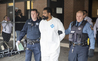 Ramapo police officers escort Grafton Thomas from Ramapo Town Hall to a police vehicle, Sunday, Dec. 29, 2019, in Ramapo, N.Y. Thomas is accused of stabbing multiple people as they gathered to celebrate Hanukkah at a rabbi's home in the Orthodox Jewish community north of New York City. (AP Photo/Julius Constantine Motal)