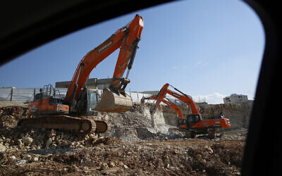 In this photo from January 1, 2019, men work on a new housing project in the West Bank settlement of Modin Illit. (AP Photo/Ariel Schalit)