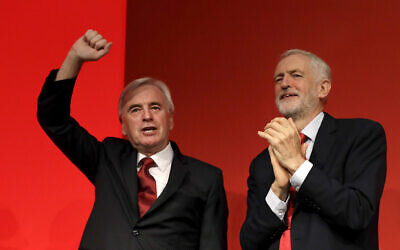 Britain's main opposition Labour Party Shadow Chancellor John McDonnell holds up his hand as party leader Jeremy Corbyn applauds after he delivered a speech during the Labour Party Conference at the Brighton Centre in Brighton, England, Sept. 23, 2019. (AP Photo/Kirsty Wigglesworth)