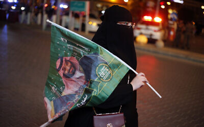 A Saudi woman holds a national flag with picture of Crown Prince Mohammed bin Salman, marking National Day to commemorate the unification of the country as the Kingdom of Saudi Arabia, in Riyadh, Saudi Arabia, September 23, 2019. (AP Photo/Amr Nabil)