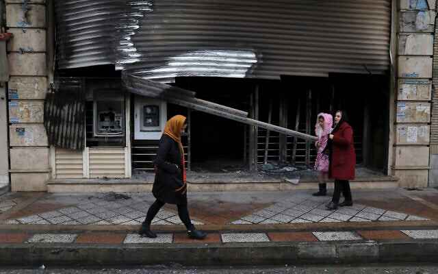 Illustrative: People walk past a bank that was burned during recent protests, in Shahriar, Iran, some 40 kilometers (25 miles) southwest of the capital, Tehran, November 20, 2019. (AP Photo/Vahid Salemi) Illustrative: People walk past a bank that was burned during recent protests, in Shahriar, Iran, some 40 kilometers (25 miles) southwest of the capital, Tehran, November 20, 2019. (AP Photo/Vahid Salemi)