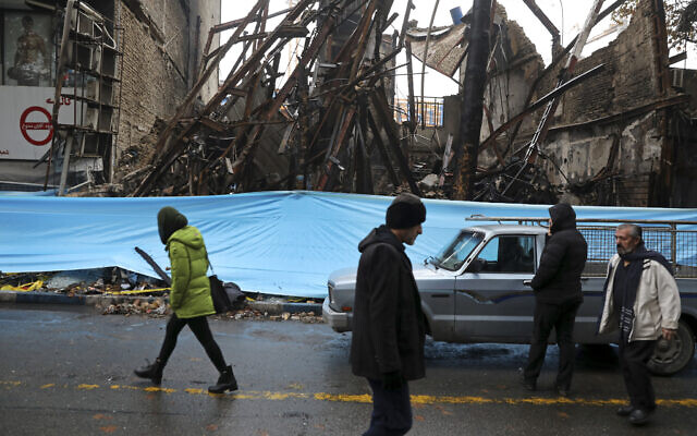 Illustrative: People walk past buildings that were burned during recent protests, in Shahriar, Iran, some 40 kilometers (25 miles) southwest of the capital, Tehran, November 20, 2019. (Vahid Salemi/AP) Illustrative: People walk past buildings that were burned during recent protests, in Shahriar, Iran, some 40 kilometers (25 miles) southwest of the capital, Tehran, November 20, 2019. (Vahid Salemi/AP)