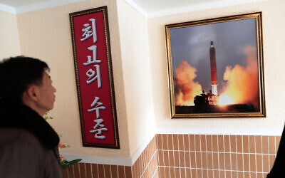 In this Nov. 26, 2019, photo, a man looks at a photo of the launch of a missile hanging on the wall of a factory workers' dormitory in Pyongyang, North Korea. (AP/Dita Alangkara)