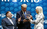 US President Donald Trump receives a menorah from Las Vegas Sands Corporation Chief Executive and Republican mega donor Sheldon Adelson, left, and his wife Miriam Adelson at the Israeli American Council National Summit in Hollywood, Florida, December 7, 2019. (AP/Patrick Semansky)