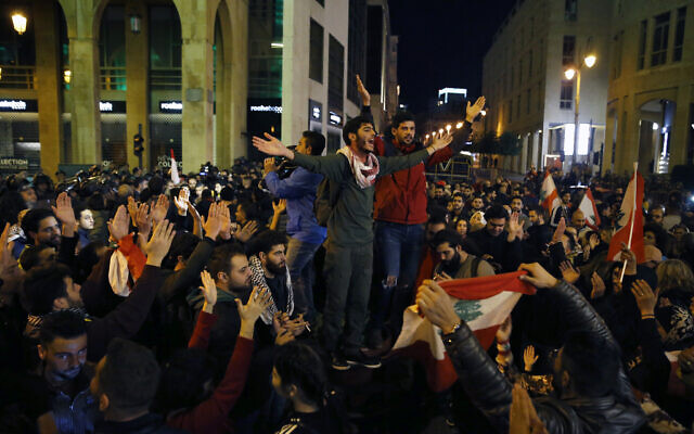 Protesters chant slogans during ongoing protests against the Lebanese political class, as riot police block a road leading to the parliament building in Beirut, Lebanon, Sunday, Dec. 8, 2019. (AP Photo/Bilal Hussein) Protesters chant slogans during ongoing protests against the Lebanese political class, as riot police block a road leading to the parliament building in Beirut, Lebanon, Sunday, Dec. 8, 2019. (AP Photo/Bilal Hussein)