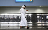 Illustrative: A worker looks at his mobile phone at Al Maktoum International Airport in Dubai, United Arab Emirates, on October 27, 2013. (Patrick Castillo/ Emarat Al Youm via AP, File)