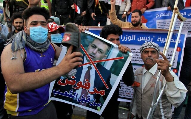 A protester hits a poster with a defaced picture of Assaad al-Aidani, the Iran-backed parliamentary bloc's nominee for the post of the prime minister, and Arabic that reads "rejected by the people," with a shoe during anti-government demonstrations in Baghdad, Iraq, December 26, 2019. (AP Photo/Khalid Mohammed) A protester hits a poster with a defaced picture of Assaad al-Aidani, the Iran-backed parliamentary bloc's nominee for the post of the prime minister, and Arabic that reads "rejected by the people," with a shoe during anti-government demonstrations in Baghdad, Iraq, December 26, 2019. (AP Photo/Khalid Mohammed)