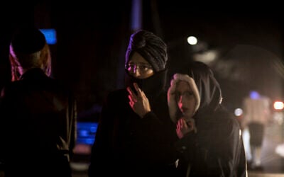Onlookers including Orthodox Jewish residents stand on the corner of Forshay Road in Monsey, New York, December 29, 2019, down the street from the scene of a stabbing rampage that occurred late the previous day during a Hanukkah celebration. (AP Photo/Allyse Pulliam)