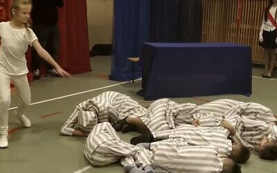 A schoolgirl dances around classmates dressed as concentration camp inmates who were gassed to death during an Auschwitz-themed event in Łabunie, Poland on December 10. (Screenshot)