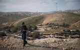 An Israeli policeman on a hilltop overlooking the West Bank Bedouin village Khan al-Ahmar on January 1, 2019. (Hadas Parush/Flash90)