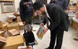 Illustrative: Rabbi Moshe Schapiro shows a toy to a child during a charity drive in Jersey City, New Jersey, Deember 23, 2019. (Courtesy Benny Polatseck/JTA)