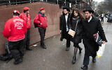 Members of the Guardian Angels, left, a volunteer safety patrol organization, stand in front of the Chabad Lubavitch World Headquarters, December 30, 2019 in the Brooklyn borough of New York. (AP Photo/Mark Lennihan)