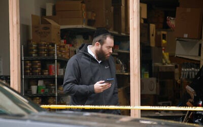 A Hasidic man stands in front of JC Kosher Supermarket in Jersey City, New Jersey, the site of a deadly anti-Semitic shooting, December 11, 2019. (Laura E. Adkins/JTA News)