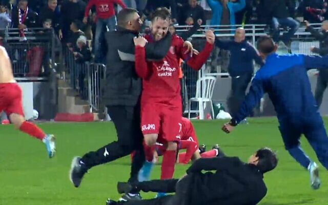 Umm al Fahm's Reef Mesika celebrates with coaches and players after beating Tel Aviv on December 21, 2019. (screen capture: Sport 5/IFL) Umm al Fahm's Reef Mesika celebrates with coaches and players after beating Tel Aviv on December 21, 2019. (screen capture: Sport 5/IFL)