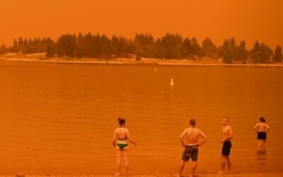 Residents take a dip to cool down at Lake Jindabyne, under a red sky due to smoke from bushfires, in the town of Jindabyne in New South Wales on January 4, 2020 (Saeed KHAN / AFP)