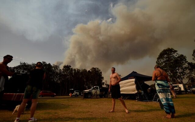 People take shelter by the beach as a bushfire burns in Batemans Bay in New South Wales on January 4, 2020 (PETER PARKS / AFP)