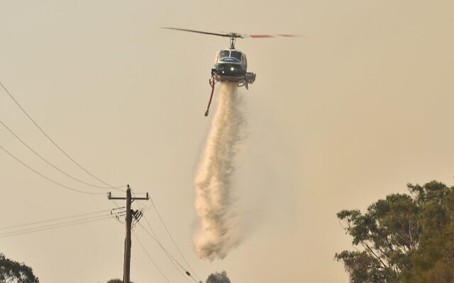 A helicopter drops water on a bushfire in Batemans Bay in New South Wales on January 4, 2020 (PETER PARKS / AFP)